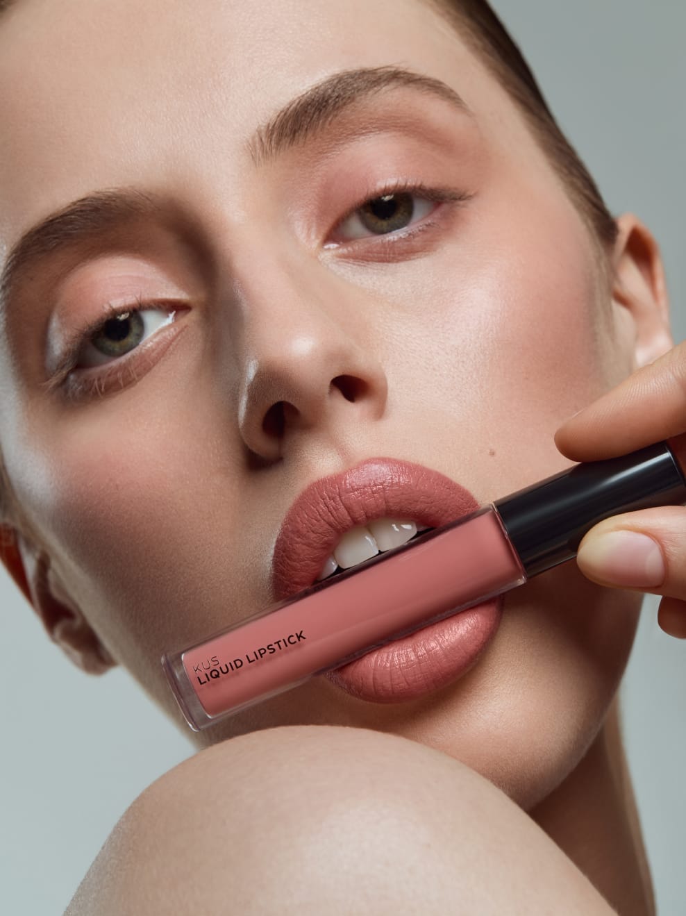 Model geschminkt mit Kus 01 und hält LipStick zwischen den Lippen