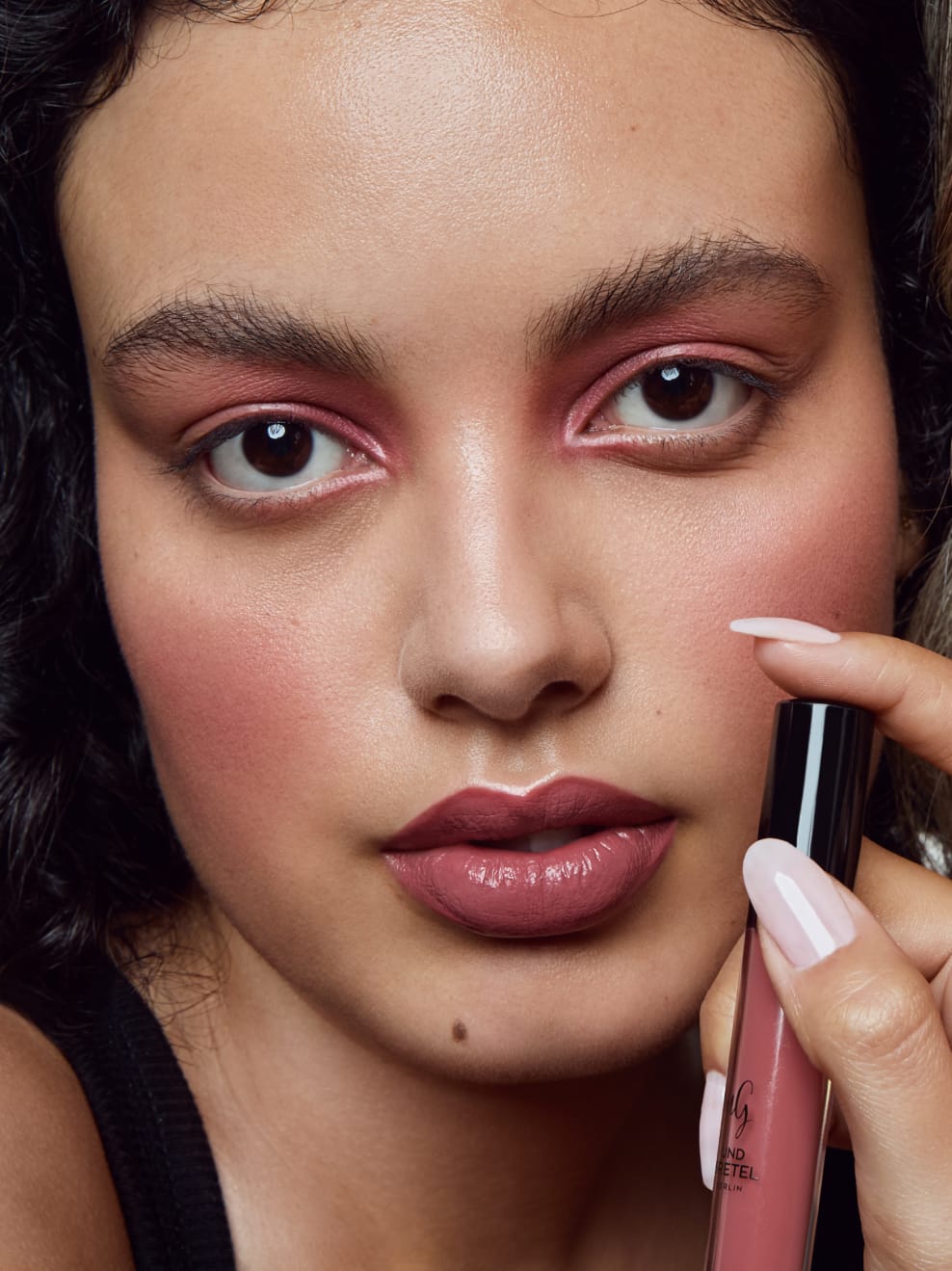Model geschminkt mit Kus 03 und hält den Lipstick in der Hand